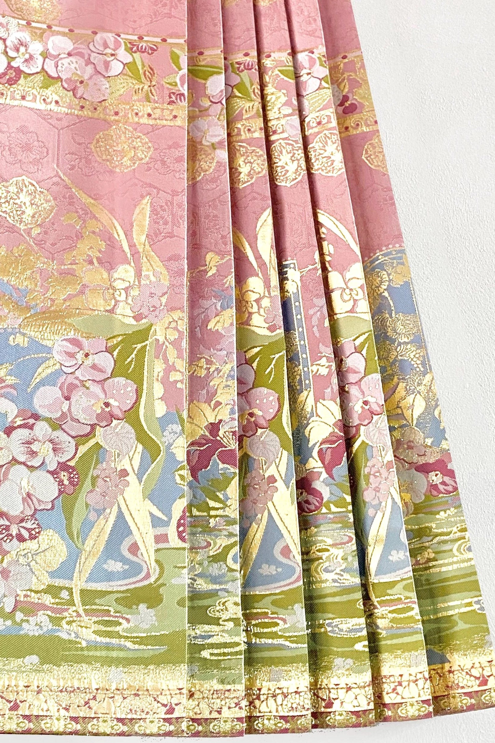 Detailed hem of pink modern Hanfu mamian skirt with gilded floral landscape pattern and structured pleats
