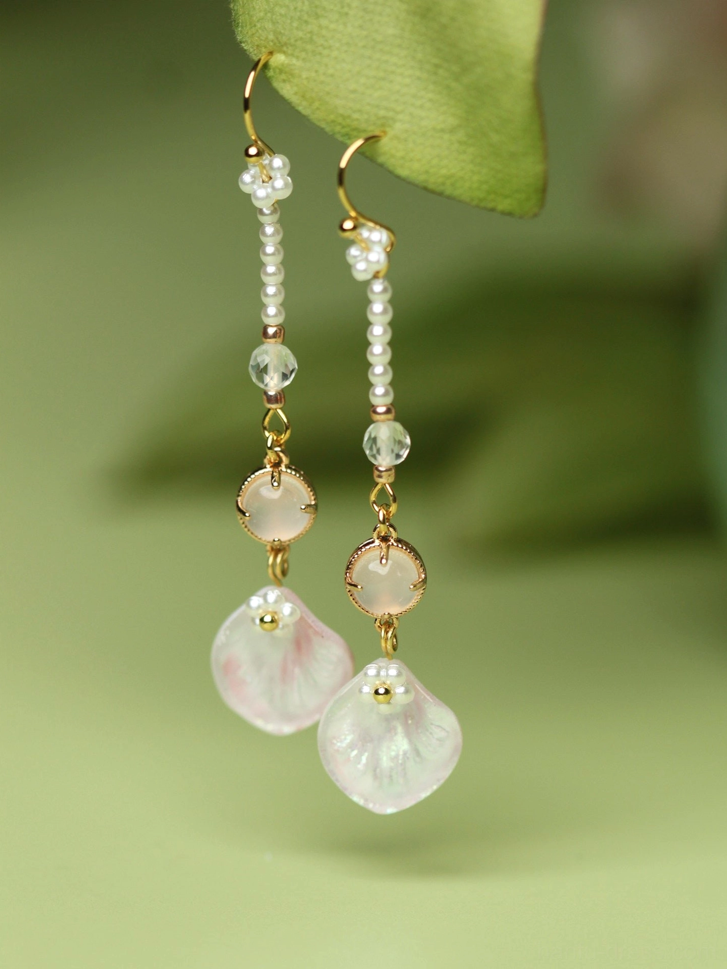 Complete pair of pink petal Hanfu dangle earrings suspended under a green leaf showing pearl crystal bead chains and translucent floral pendants