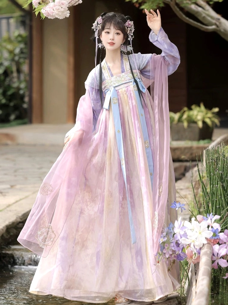 Side three quarter view of a woman in a pink purple gradient Qixiong Ruqun Hanfu dress beside a traditional Chinese courtyard and cherry blossoms