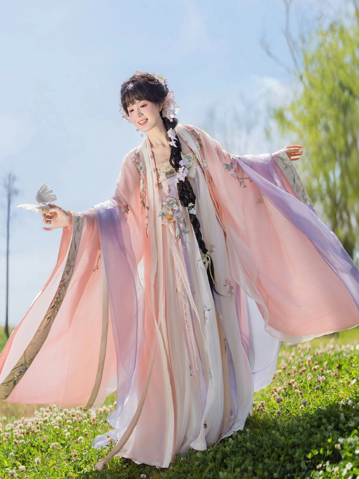 Pink and purple Tang-style Qixiong Ruqun hanfu outer coat with flowing wide sleeves modeled outdoors on a sunny lawn