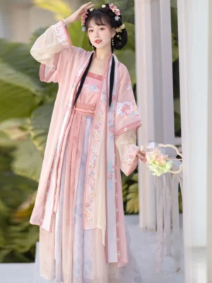 Pink Song Dynasty style Qiyao Ruqun Hanfu outfit shown from a three-quarter angle with floral embroidery, flowing skirt layers, traditional hair ornaments, and garden-inspired styling