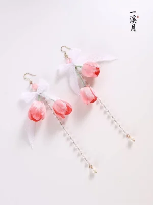 Angled view of a symmetrical pair of pink tulip bow Chinese earrings with delicate gold chains and pearl-inspired hanging accents