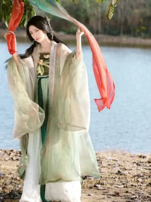 Pipa Beauty Tang Dynasty style Heziqun Hanfu dress in pale green with embroidered tube top, layered skirt, and sheer wide sleeve coat shown in a lakeside outdoor setting