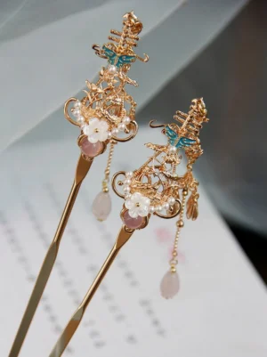 Traditional Chinese hair stick with pink gemstone accent, white floral decoration, blue enamel detail and soft pink tassel on decorative paper