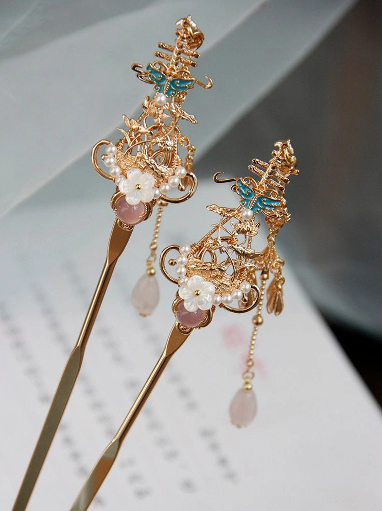 Traditional Chinese hair stick with pink gemstone accent, white floral decoration, blue enamel detail and soft pink tassel on decorative paper