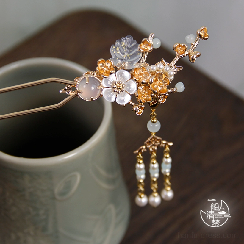 Plum blossom and snow Chinese hair stick with white flowers golden branches agate beads and long pearl tassels on wooden table