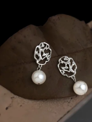 Plum blossom window pearl drop Hanfu earrings displayed on a dried leaf against a dark background