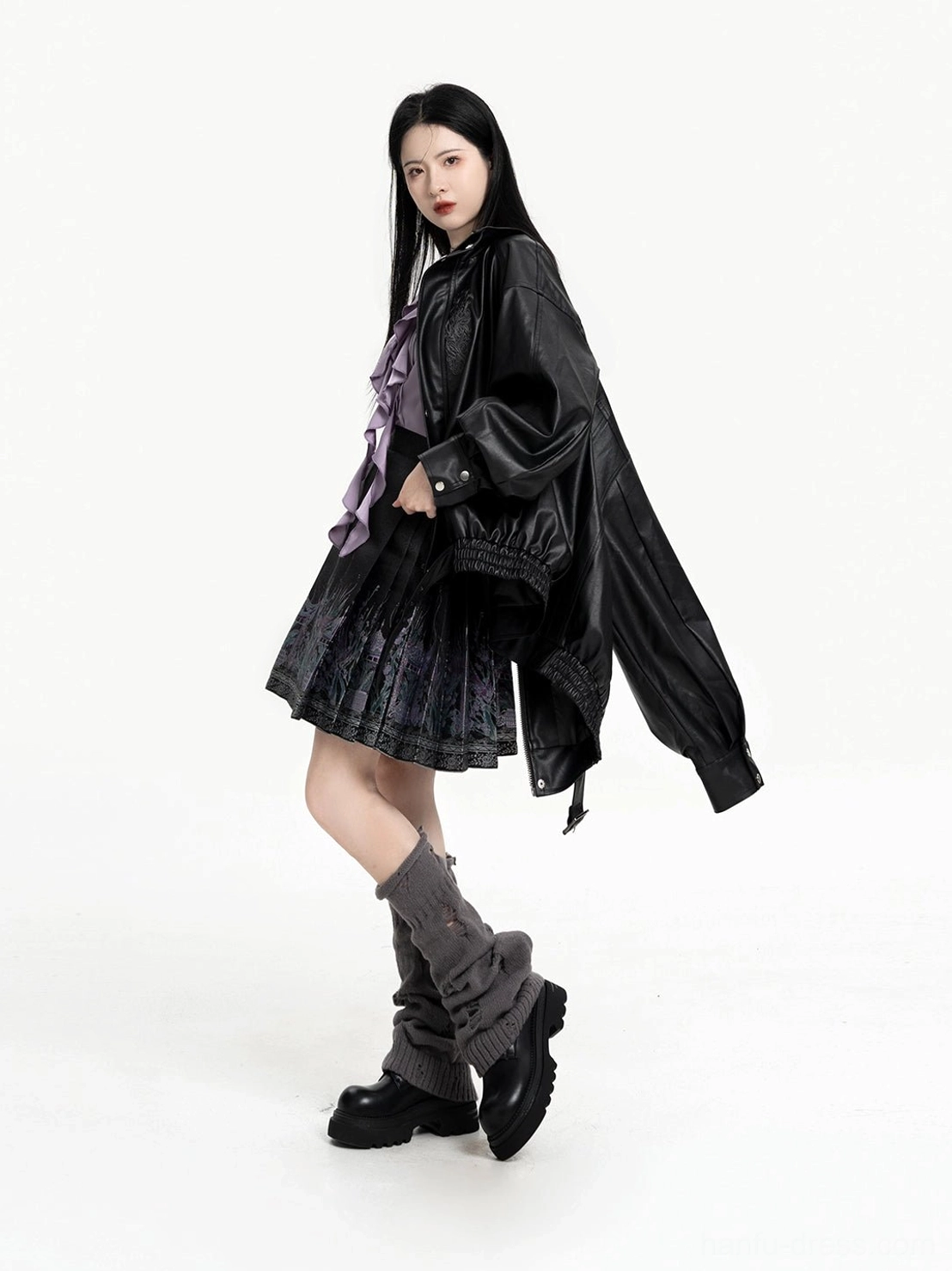 Side full-body view of black faux leather coat and pleated phoenix mini mamian skirt Chinese-inspired outfit