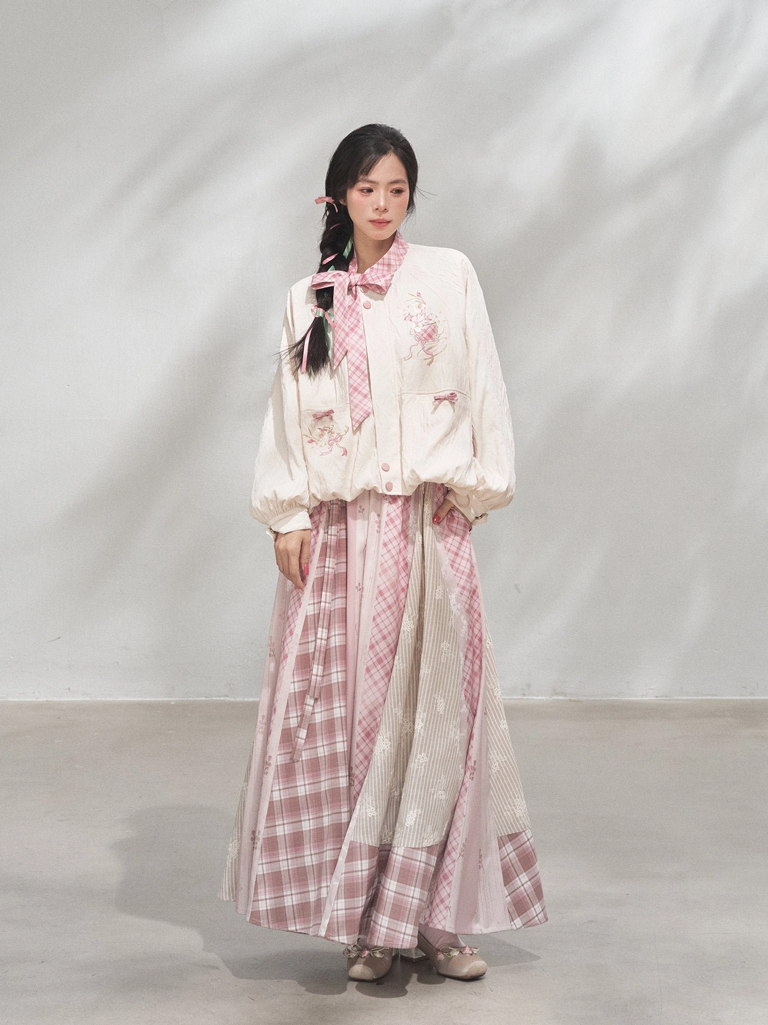 Front full-body view of a modern Hanfu xianxia coat and patchwork maxi skirt outfit in cream and powder pink with floral embroidery and puff sleeves
