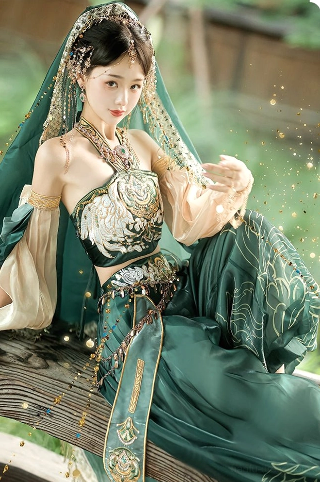 Three-quarter front sitting view of a Princess Jasmine inspired Dunhuang Feitian costume with embroidered bustier, satin fabric, gold trim, delicate hair jewelry, and celestial styling