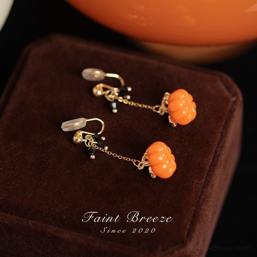 Pumpkin lantern comfort clip on Chinese earrings displayed on a brown velvet jewelry box with orange pumpkin themed decoration