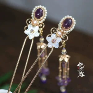 Vintage Chinese purple tassel hair pin with gold-tone frame oval purple gemstone pearl border white shell flower charm and dangling beaded tassel displayed on dark wood