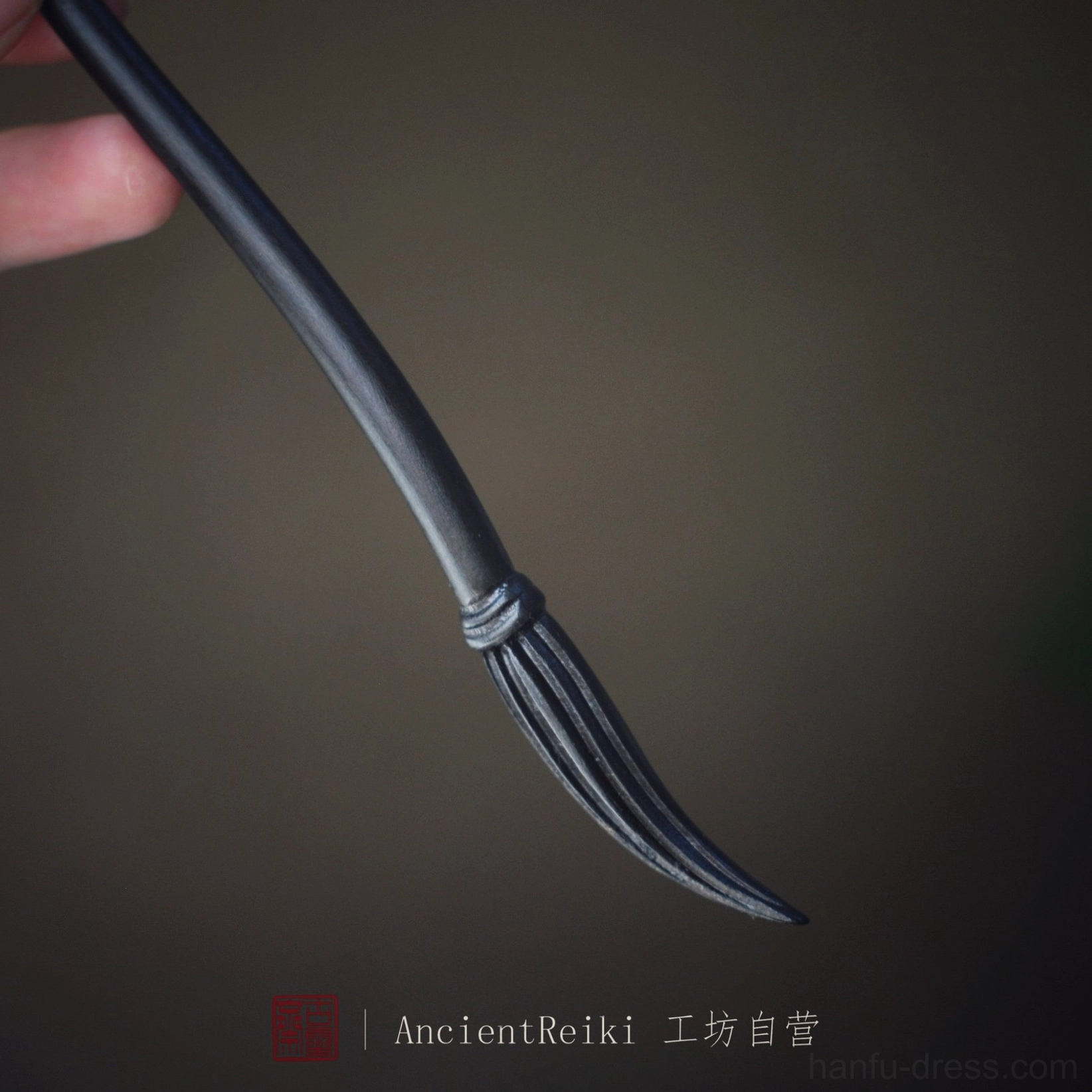 Purple black Chinese ink brush hair stick in hand featuring a smooth curved body and carved brush bristle texture