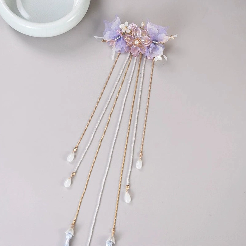 Overhead flat lay of a purple Chinese hair pin with mixed gold and white chains clear pendants and blue tassel ends