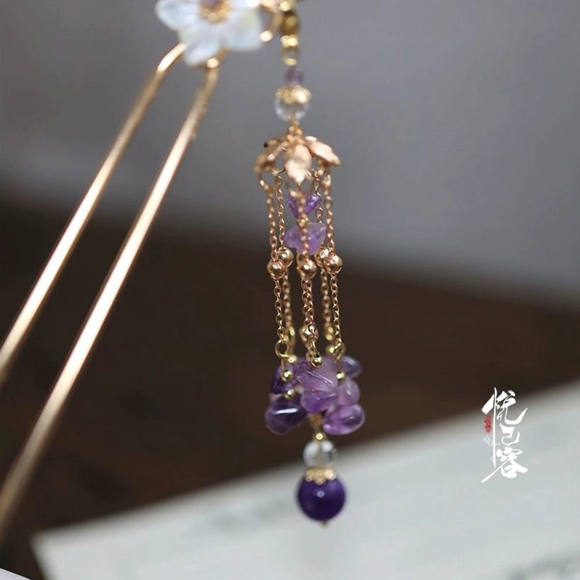 Close-up of dangling Chinese hair pin tassel featuring delicate gold chains purple gemstone beads and a dark round purple pendant
