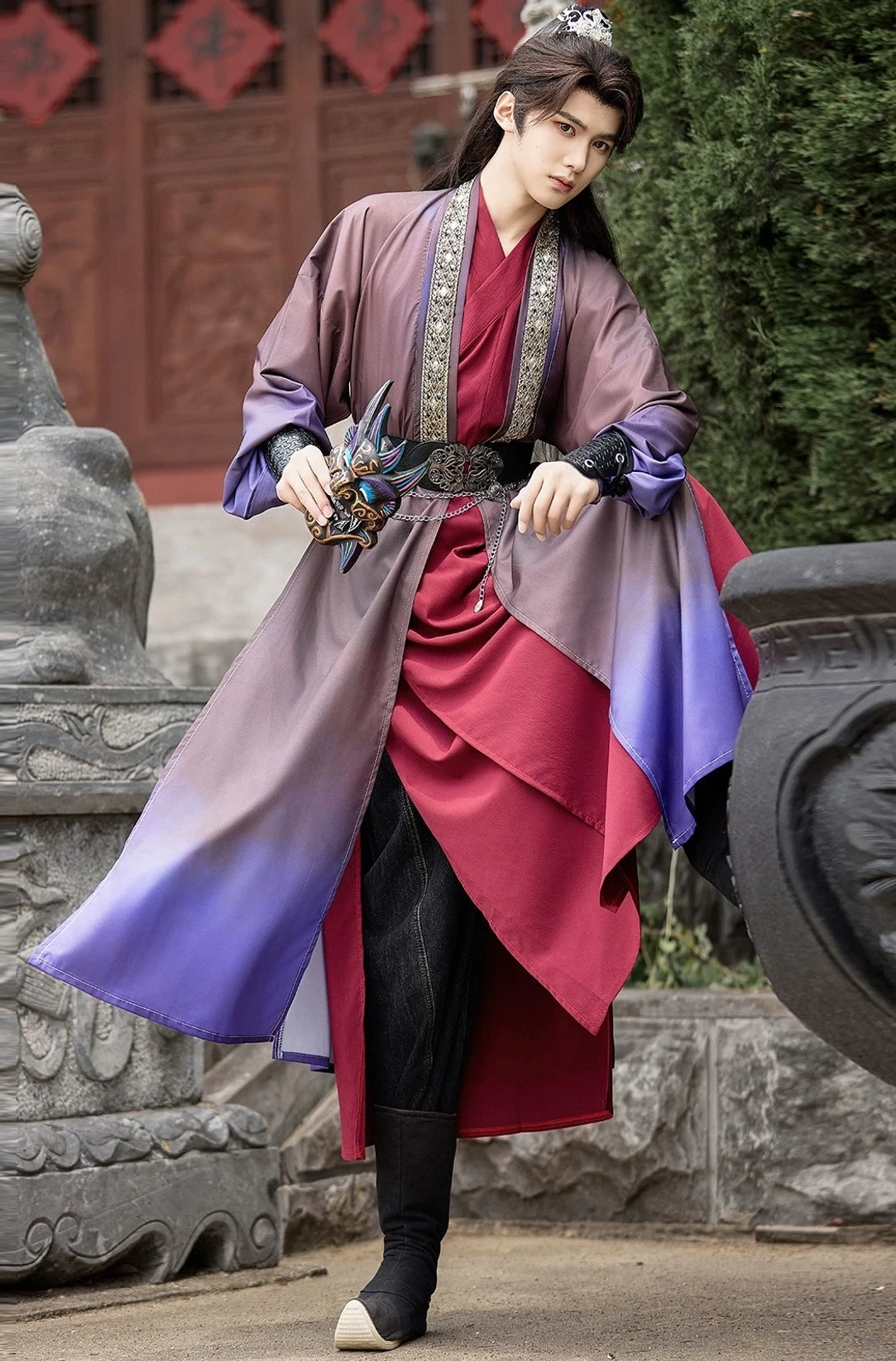 Men's Hanfu Ghost King cosplay robe set with dark taupe and lavender purple gradient, embroidered cross-collar trim, waist belt, ghost mask, and traditional-style boots in an ancient Chinese courtyard