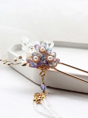 Close-up of a purple floral butterfly Chinese hair stick with gold-tone filigree, faux pearls, and a long white beaded tassel displayed on a white tray