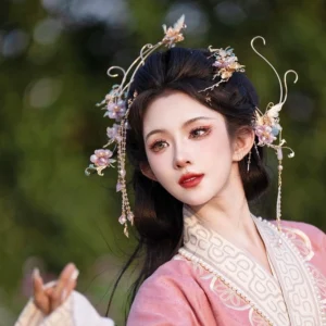 Side three-quarter view of a woman wearing traditional pink Hanfu and purple Chinese hair accessories with delicate floral ornaments and flowing tassels