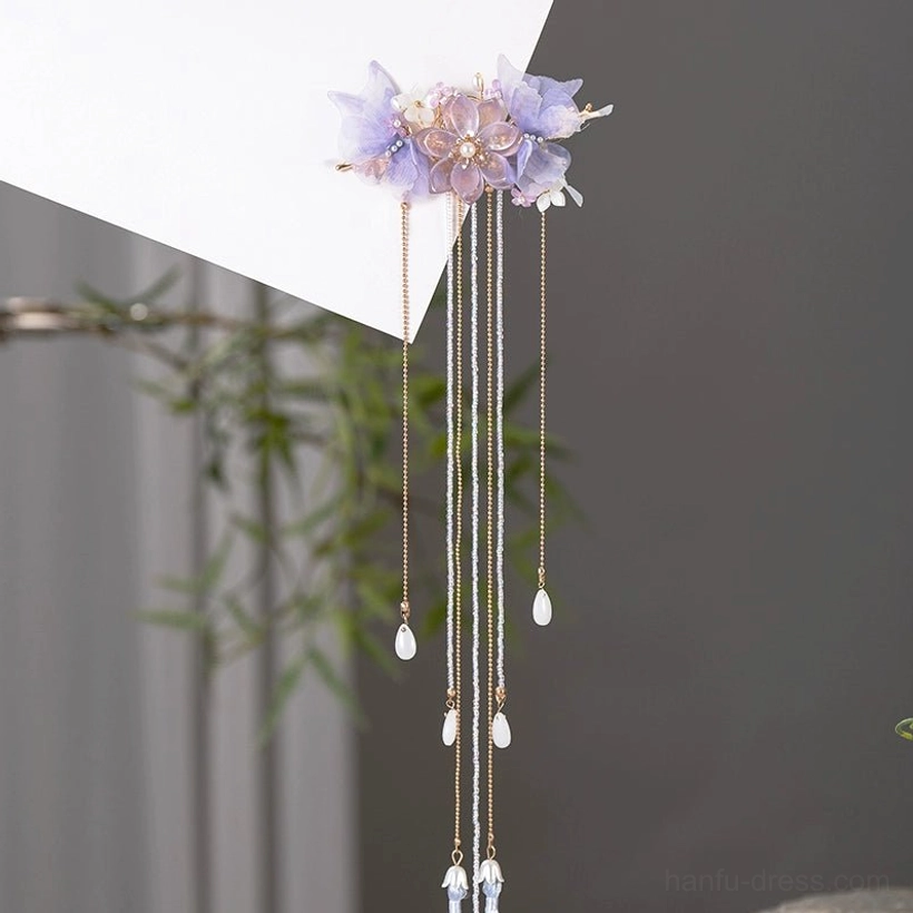 Oblique view of a purple floral Hanfu hair pin with gold chains blue purple tassels and glass teardrop ornaments
