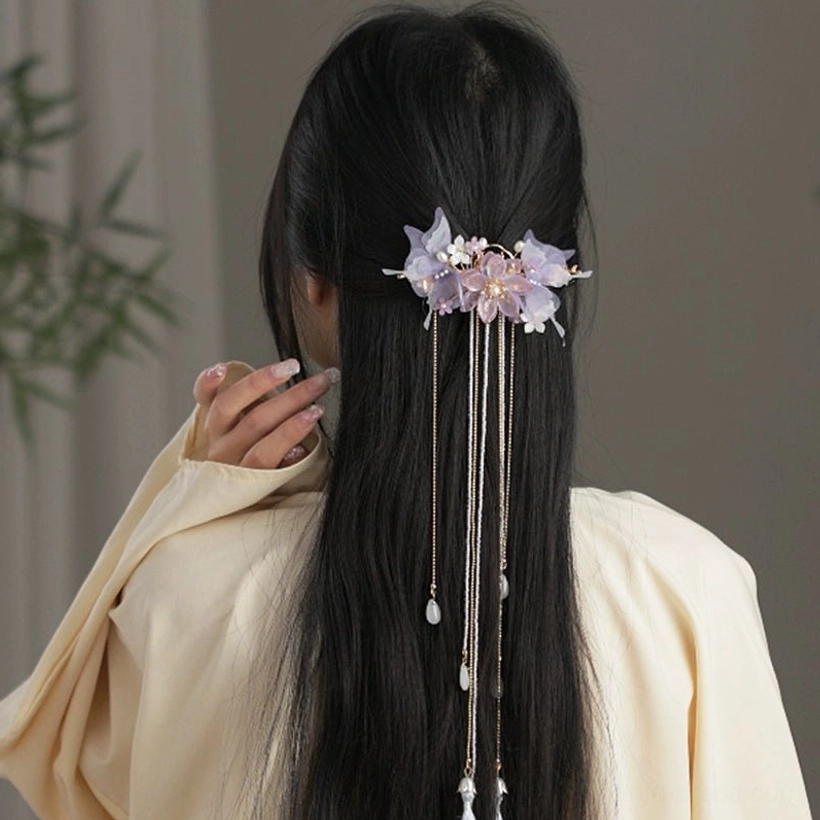 Purple floral Hanfu hair accessory worn in a half up hairstyle with delicate gold chains and glass teardrop charms