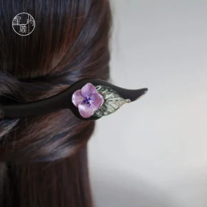 Purple hydrangea flower Chinese hair stick styled in long brown hair from the back, featuring a black wooden pin and green leaf Hanfu hair accessory