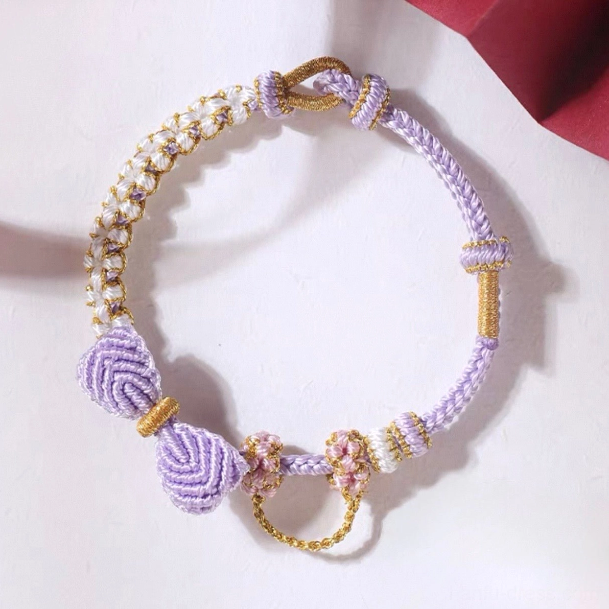 Purple and ivory handwoven Chinese knot bow bracelet with flower knots, pearl-like beads, and gold-tone accents