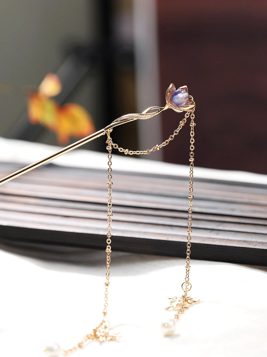 Purple lotus tassel Chinese hair stick for Hanfu shown in an overhead close-up with gold-tone pin, double chain tassels, pearl pendants, and snowflake charms