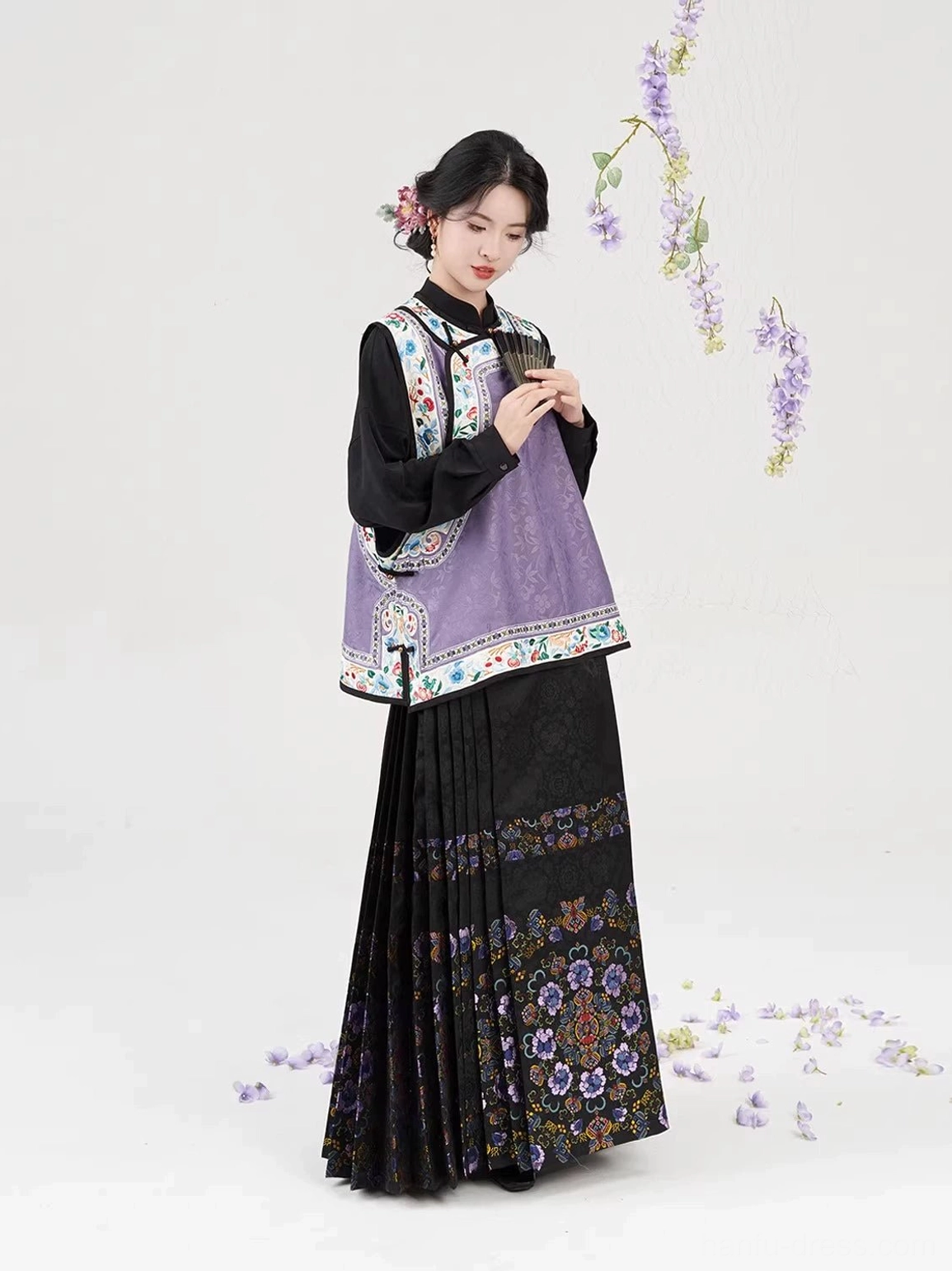 Women wearing purple Qing-inspired jacquard vest and black pleated mamianqun Hanfu outfit three-quarter side view
