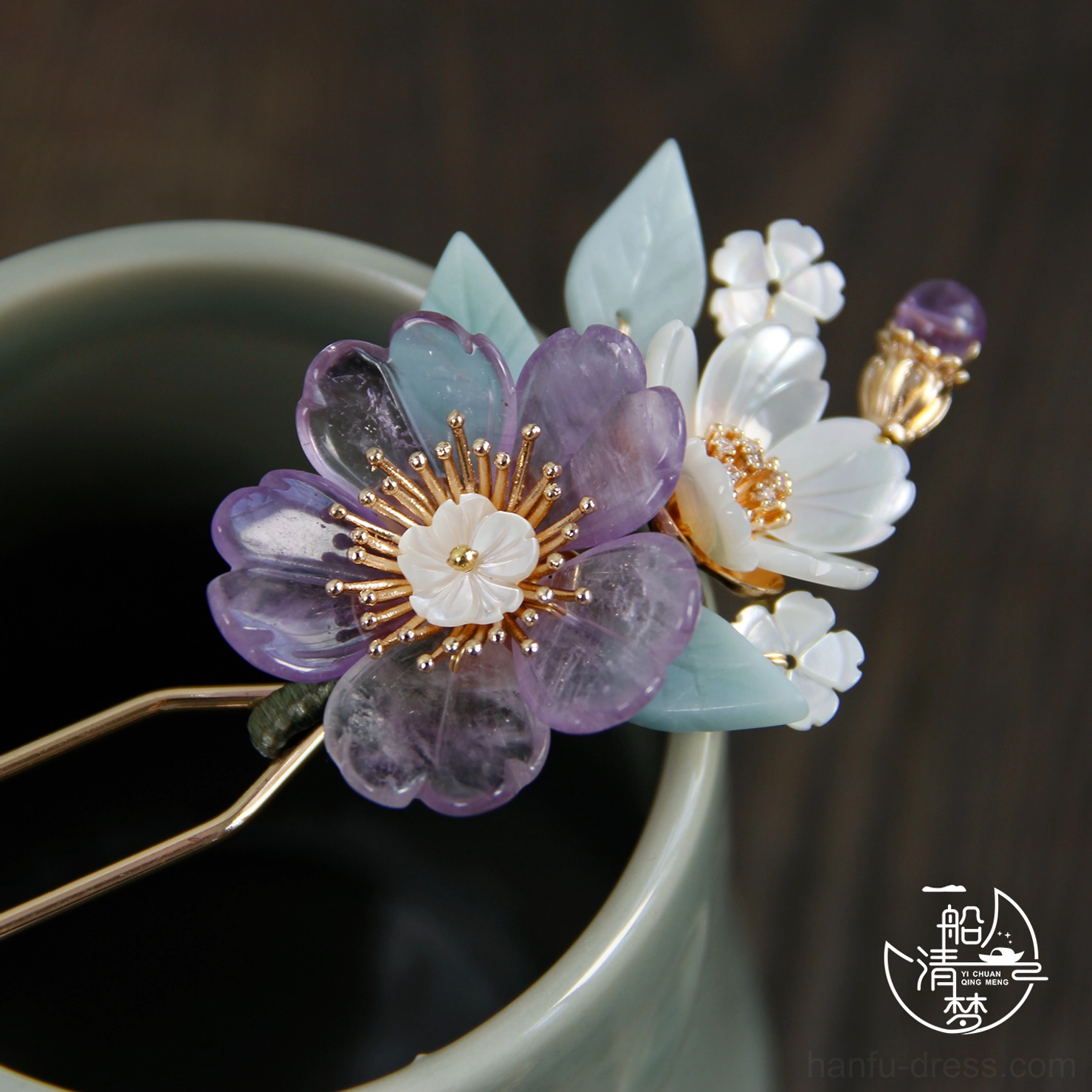 Close-up of a purple resin flower hair stick with white shell-like blossoms and light blue decorative leaves