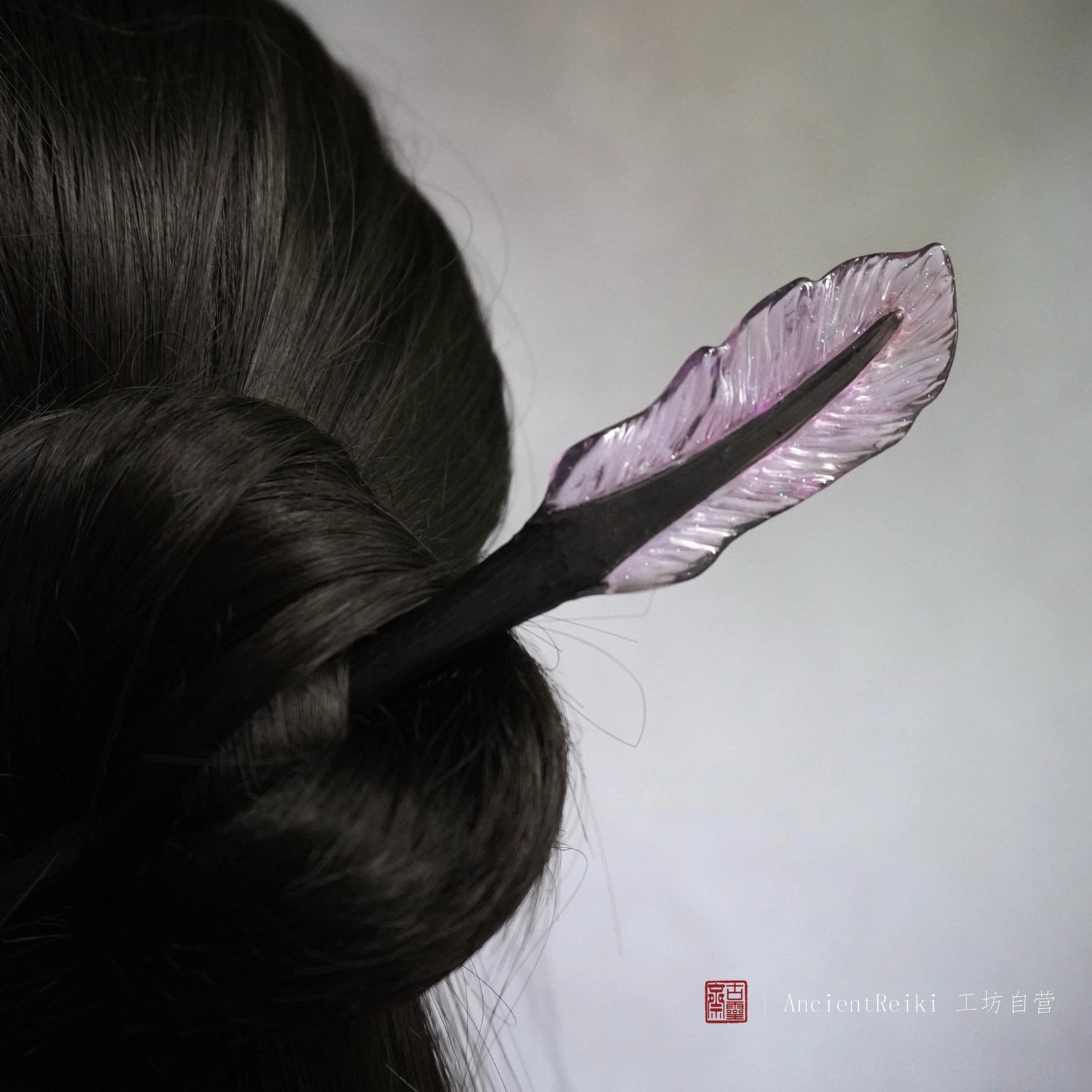 Purple translucent feather Chinese hair stick worn in a dark coiled updo, elegant Hanfu hairstyle accessory back view