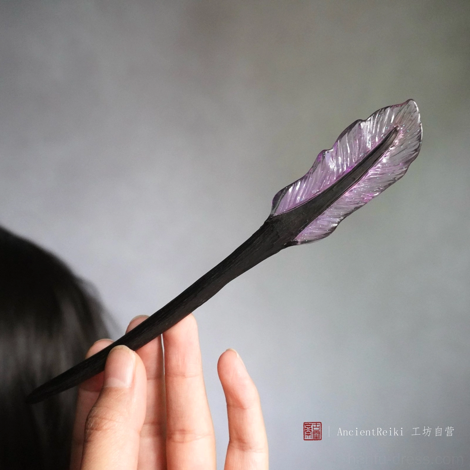Side close-up of purple translucent feather hairpin with detailed feather veins and black wooden stick for Hanfu hairstyles