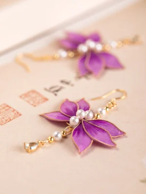 Pair of purple velvet flower Hanfu earrings with gold trim pearl centers and dangling teardrop accents on vintage stationery