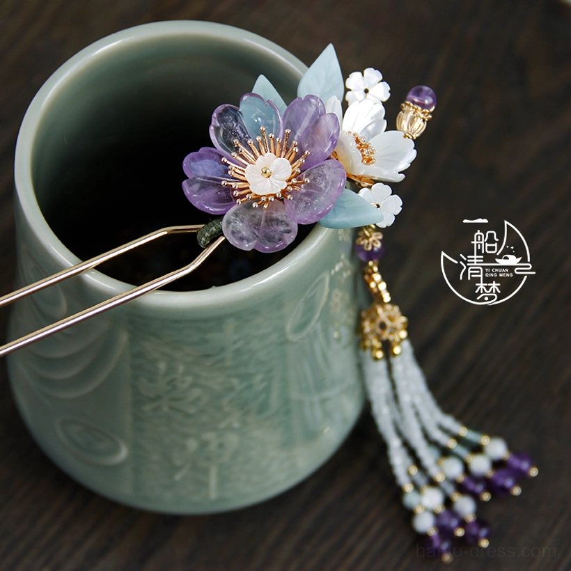 Purple and white traditional Chinese flower hair stick with light blue leaves displayed on a carved celadon ceramic cup