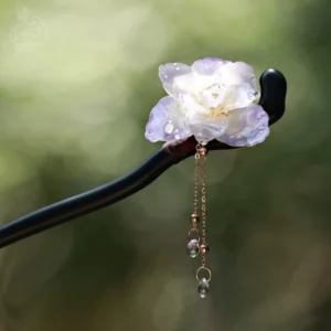 Purple and white gradient flower tassel Chinese hair stick with dark wooden hairpin rod and golden crystal drop pendants displayed against blurred green foliage