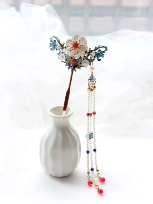 Qingdai cloisonne flower tassel Chinese hair stick displayed in a white ceramic vase with blue enamel floral details pearl strands and red bead pendants