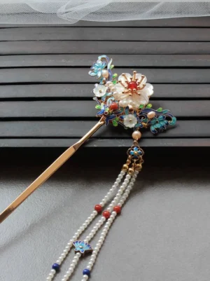 Traditional Chinese flower hair stick on dark wood featuring shell blossom blue cloisonne-style ornaments and multi-strand pearl tassel