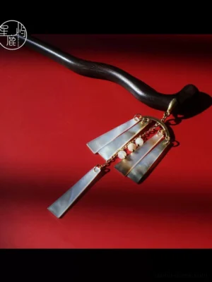 Qingfeng mother-of-pearl tassel Chinese hair stick with curved dark pin, gold-tone chains and iridescent pendant on red background
