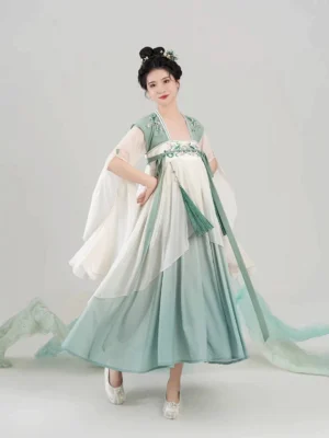 Three-quarter front view of Qintaoluoge Tang-style Hanfu dress showing floral embroidered chest panel, decorative waist sash, long tassel pendant, and flowing gradient skirt