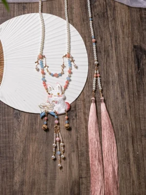 Traditional rabbit lotus Hanfu necklace with layered beaded side chains, pink back tassels, floral charms, and round fan on dark wood
