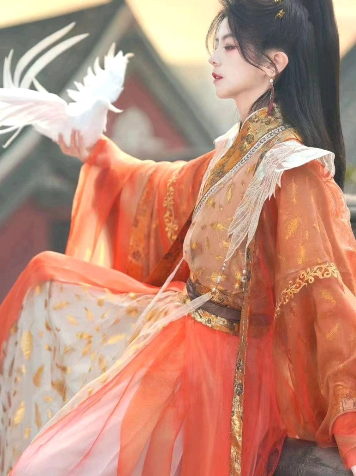 Radiance fantasy hanfu costume seated side view showing embroidered golden cuffs, layered feather motif skirt, and long flowing sleeves