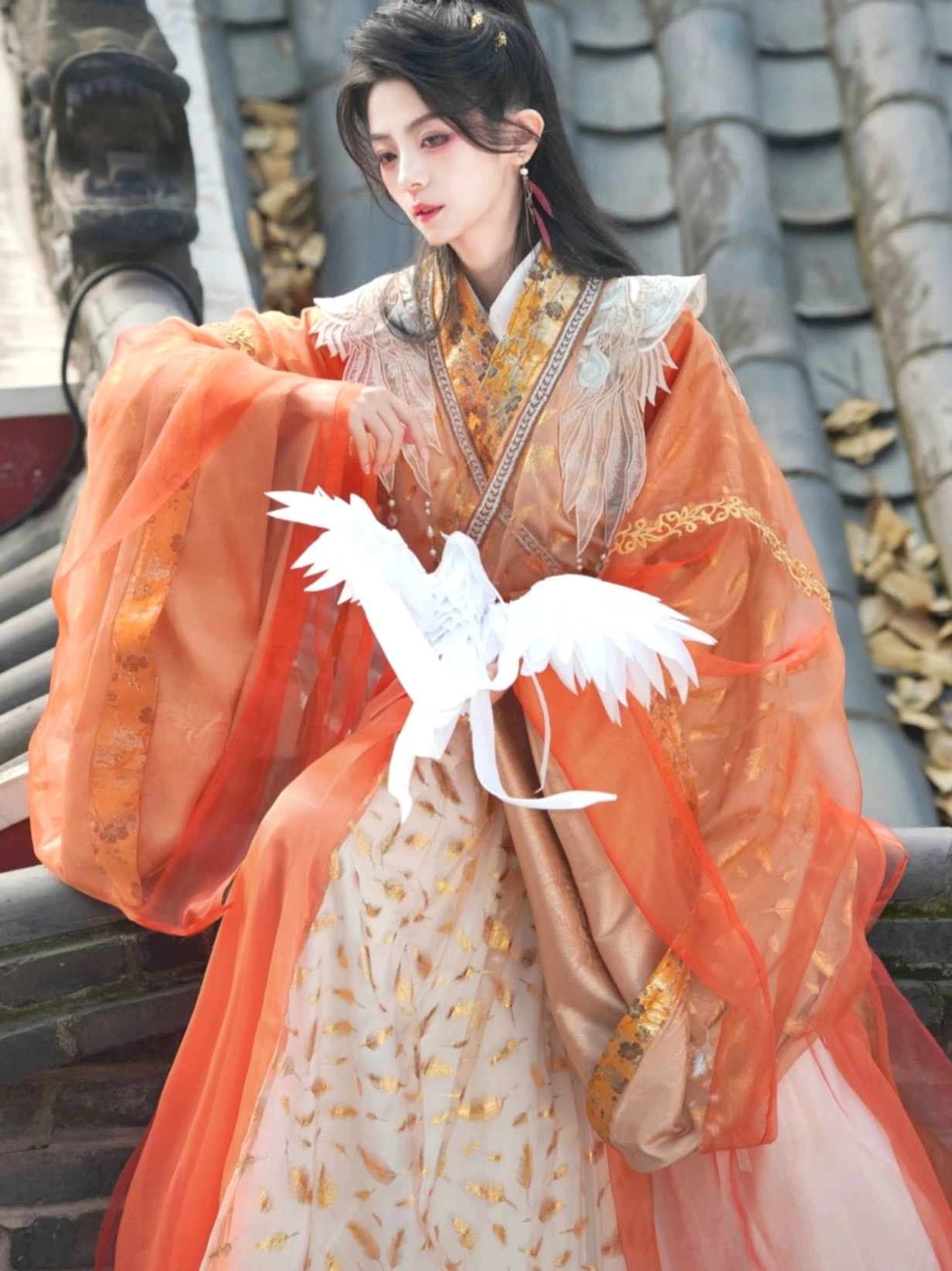Radiance gender-neutral xianxia hanfu costume in orange and gold with flowing sheer sleeves, golden feather skirt, wing embroidery, and paper crane