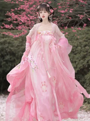 Pink Tang Dynasty Qixiong Ruqun Hanfu with sheer wide sleeves, floral printed skirt, chest ornament, and tassel accessories in a blooming garden