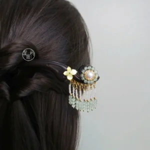 Traditional Chinese hair stick with dark wooden base, golden floral ornament, faux pearl, and light green beaded tassel styled in a half-braided long hairstyle