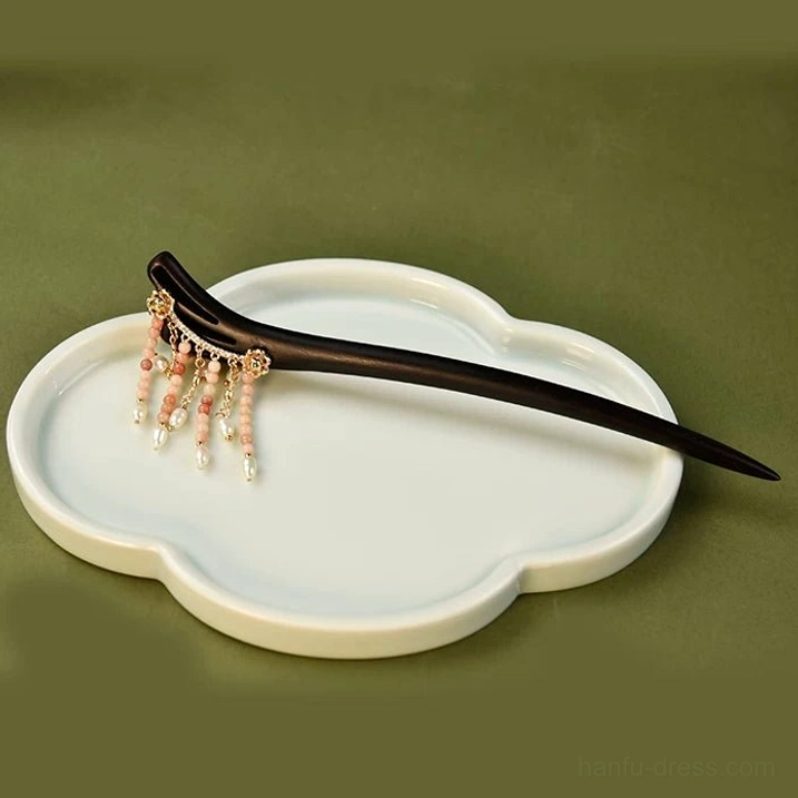 Full length view of Raining Petals Chinese hair stick with slim black wooden pin and compact pink pearl tassel ornament on white tray