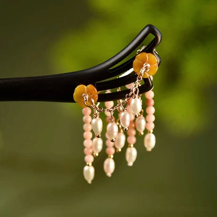 Chinese Hanfu hair stick close-up featuring yellow flower ornaments, pale pink beads, white freshwater pearl tassels and gold connectors
