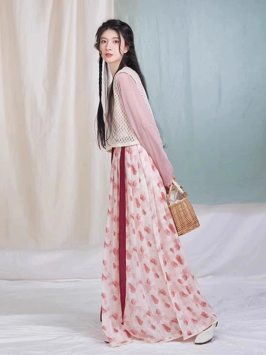 Full-length side view of a model wearing a raspberry-print Tang Dynasty hanfu set with dusty pink top, beige crochet beizi, wine-red sash, and pleated skirt