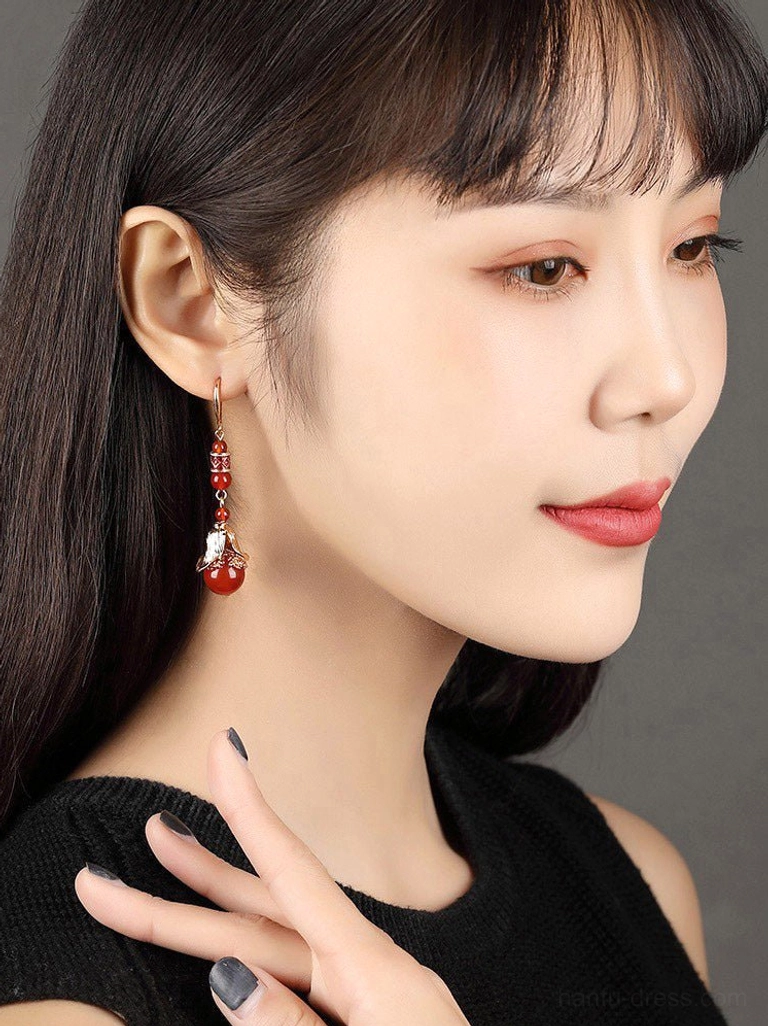 Side portrait showing red agate dangling cheongsam earrings worn with a black top, highlighting the long tiered silhouette