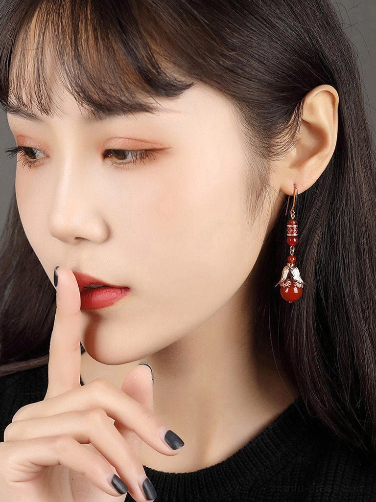 Woman wearing red agate Chinese dangling earrings with floral enamel details for an elegant modern traditional jewelry look