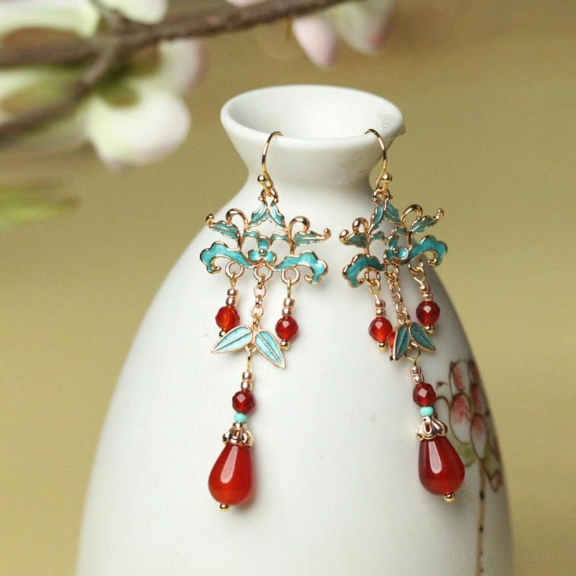 Hook style red agate cloisonne drop earrings displayed beside a white porcelain vase with soft floral background