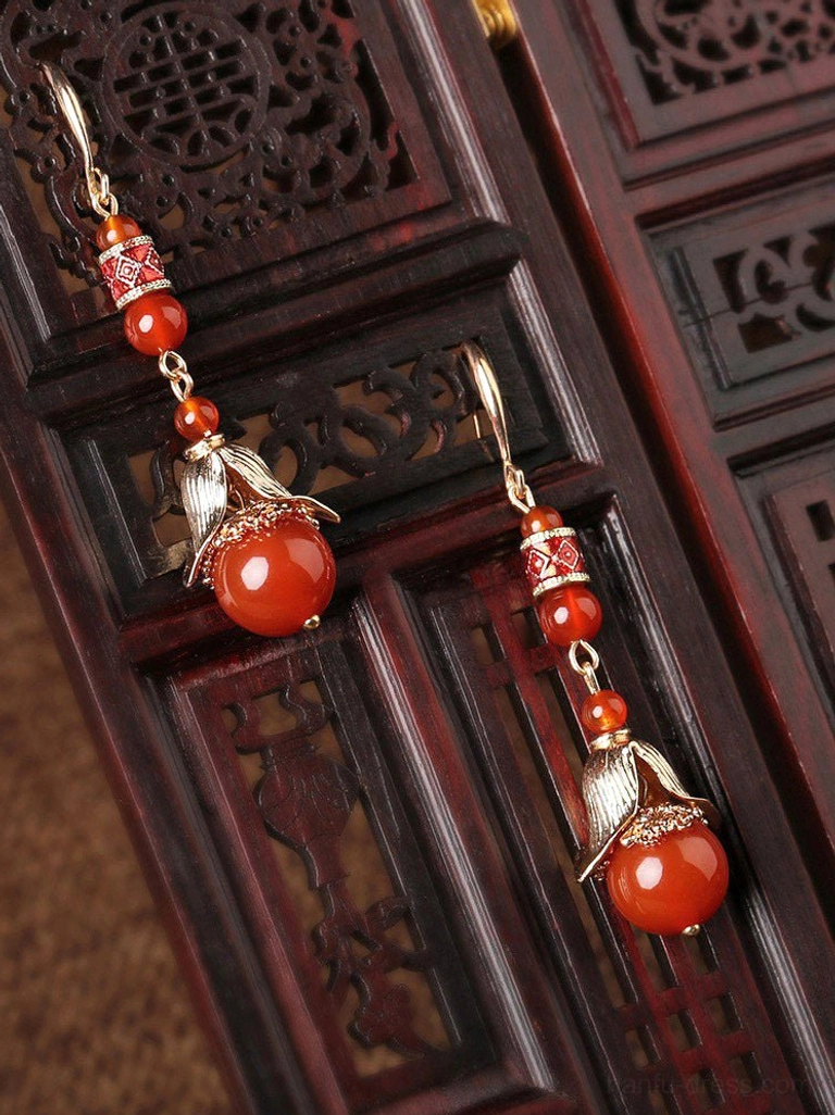 Red agate vintage drop earrings displayed on carved dark red Chinese-style wood with antique-inspired metal ornament details